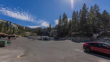 A parking area with RVs and cars, surrounded by trees and buildings.