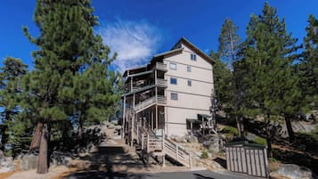 A multi-story building with a staircase leading to an upper level, surrounded by trees and rocks.