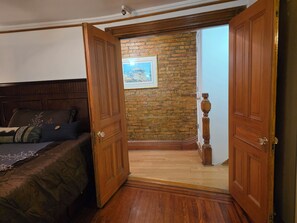 Ein Schlafzimmer mit einem hölzernen Bett, einer Ziegelwand und einer Tür zu einem anderen Raum.