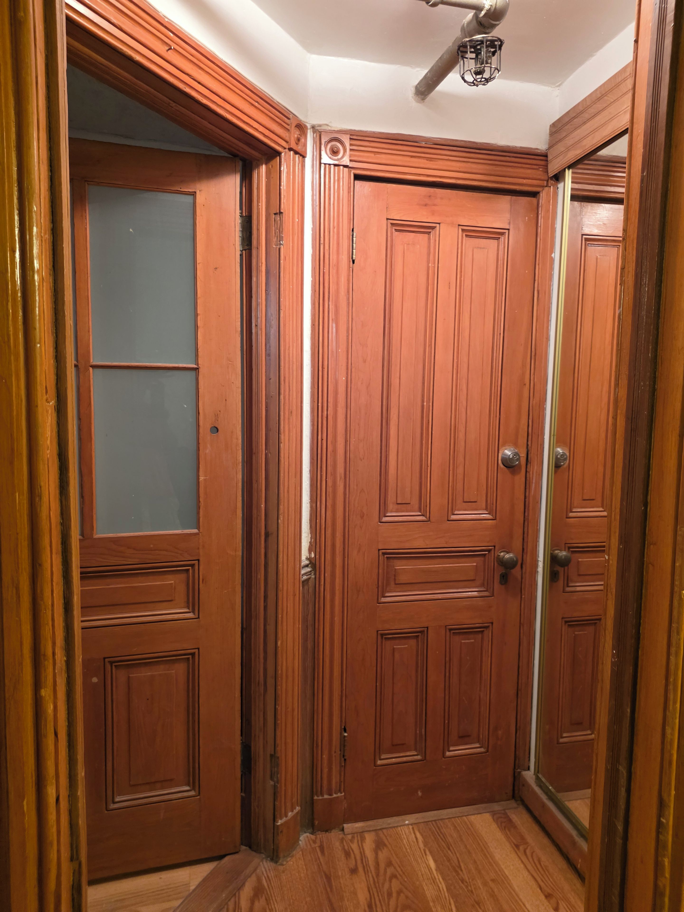A corner room with wooden doors, a ceiling fan, and a wooden floor.
