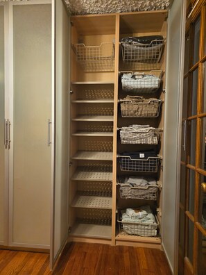 Ein begehbarer Kleiderschrank mit mehreren Regalen und Drahtkörben zur Aufbewahrung.