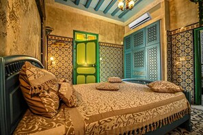 Una habitación con una cama, paredes con diseño y una puerta verde.