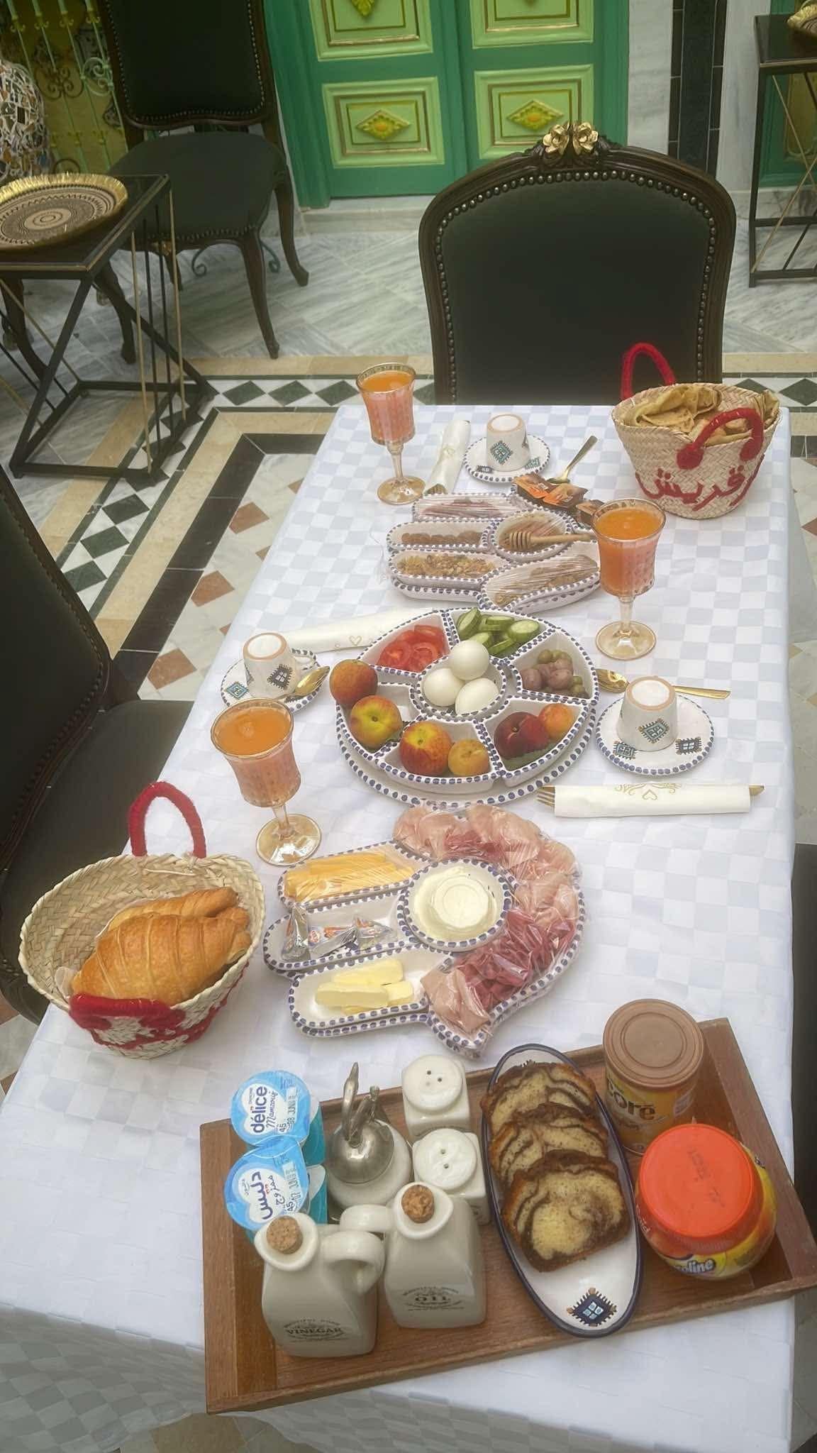 A table set with a variety of food items, including fruits, cheeses, and bread, suggesting a breakfast or brunch setting.