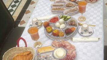 A table set with a variety of food items, including fruits, cheeses, and bread, suggesting a breakfast or brunch setting.