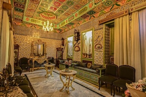 Una habitació amb paper pintat decoratiu, un penjallum i mobles tradicionals.