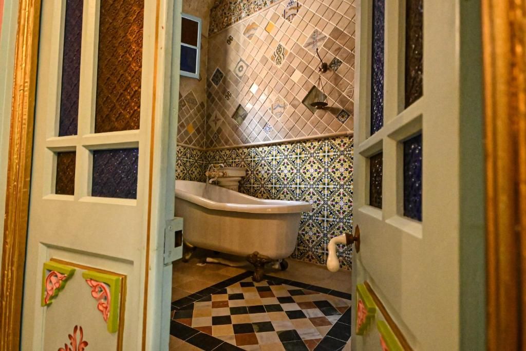 A bathroom with a vintage clawfoot bathtub, patterned tiles, and a checkered floor.