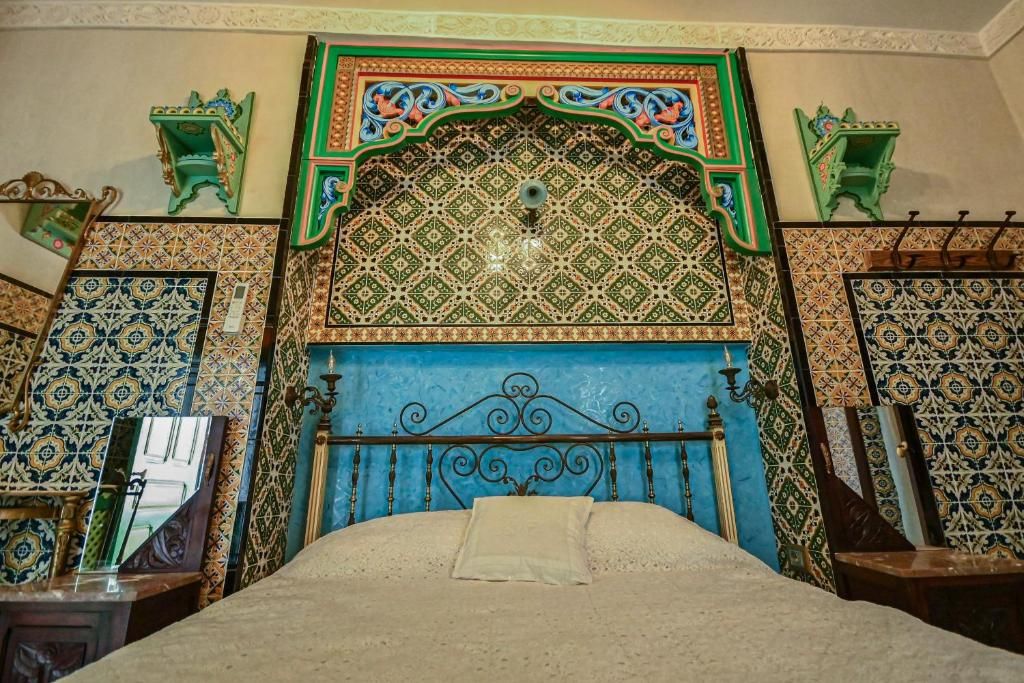 Quarto com teto estampado, cabeceira azul e detalhes decorativos nas paredes.