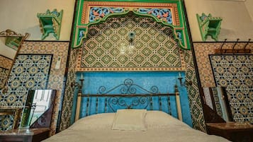Quarto com teto estampado, cabeceira azul e detalhes decorativos nas paredes.