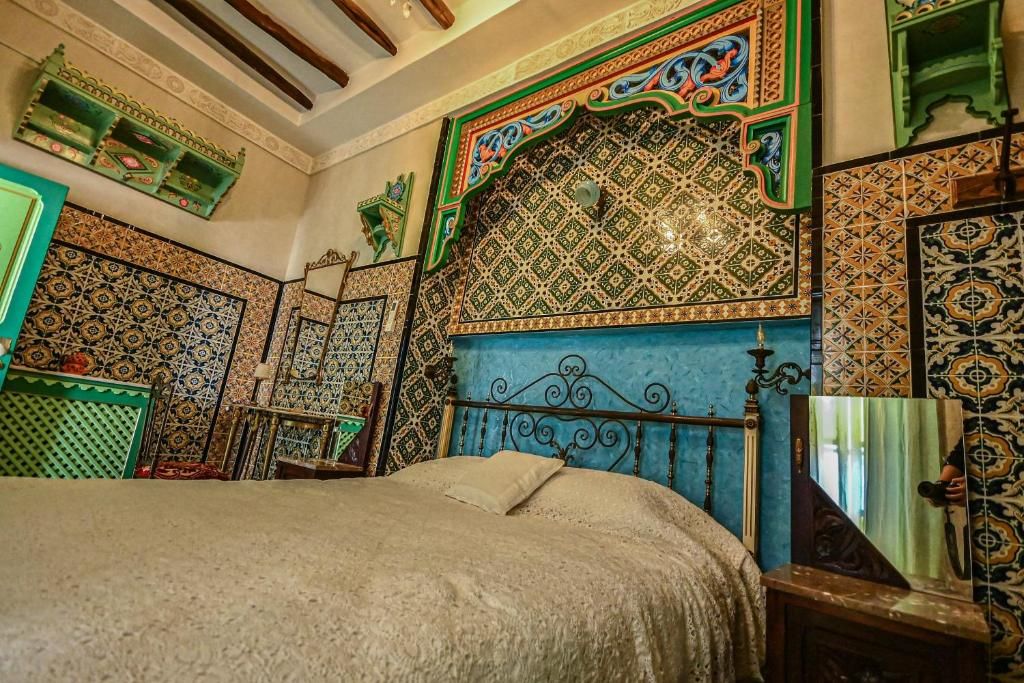 A room with a bed, ornate wall tiles, and a decorative headboard.