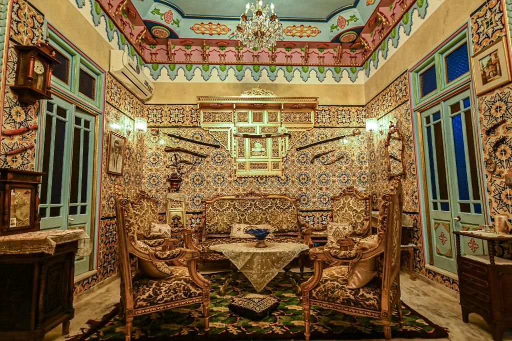 A room with ornate tile walls, a chandelier, and traditional furniture.