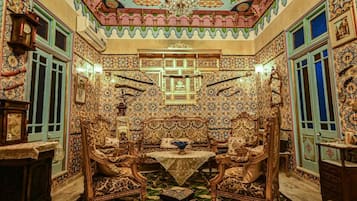 A room with ornate tile walls, a chandelier, and traditional furniture.