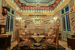 A room with ornate tile walls, a chandelier, and traditional furniture.
