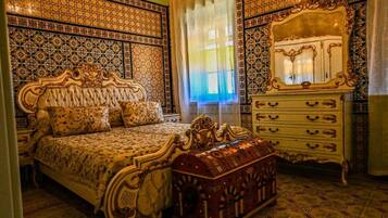 Ein Schlafzimmer mit einem großen Bett, einem verzierten Schmuckkästchen und Wandmustern.