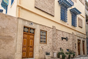 A building with ornate wooden doors, decorative window grills, and a stone facade.