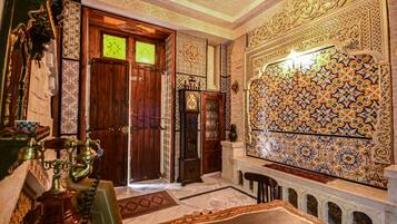 An ornate room with intricate tile work, a wooden door, and a traditional water fountain.