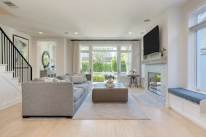 A modern living room with a grey sofa, a coffee table, and a fireplace. - Stunning Home, Mins to Beach, Perfect for Families W/AC! (Newport Beach)