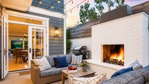 Eine Terrasse im Freien mit Kamin, Korbmöbeln und Lichterketten.