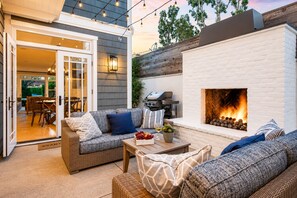 An outdoor patio with a fireplace, wicker furniture, and string lights. - Mins To Newport Beach, Pier, Water-Front Dining (Newport Beach)