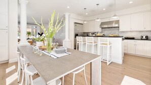 Eine moderne Küche mit weißen Schränken, einem Holztisch und Pendelleuchten.