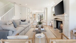Ein modernes Wohnzimmer mit Kamin, einer Couch, einem Couchtisch und einem Fernseher.