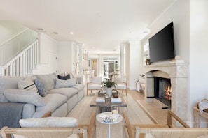 A modern living room with a fireplace, a sofa, a coffee table, and a television. - Mins To Newport Beach, Pier, Water-Front Dining (Newport Beach)