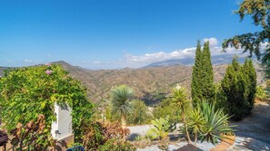 A garden with various plants and a view of distant hills. - La Casita Sayalonga by Ruralidays (Málaga)