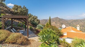 A wooden pergola with seating, surrounded by Mediterranean vegetation, overlooking a mountainous landscape. - La Casita Sayalonga by Ruralidays (Málaga)