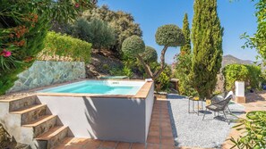 A swimming pool with a stone wall, steps leading up to it, and a chair and table nearby. - La Casita Sayalonga by Ruralidays (Málaga)