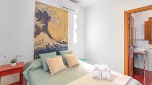 A hotel room with a bed, a nightstand, a wall-mounted air conditioner, a small plant, and a view of the bathroom through an open door. - La Casita Sayalonga by Ruralidays (Málaga)