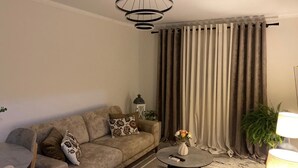 Un salon avec un canapé, une table basse, une lampe et des rideaux.