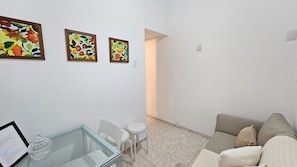A living room with a sofa, a glass table with a decorative item, and three framed floral paintings on the wall. - Copa Central Praia a Poucos Minutos (Rio de Janeiro)