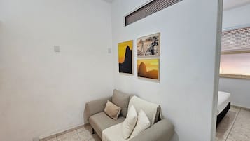Una stanza con un divano grigio, due cuscini e tre quadri appesi al muro.