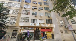 A multi-story building with air conditioning units, a storefront with signage, and a no parking sign. - Copa Central Praia a Poucos Minutos (Rio de Janeiro)