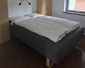 A single bed with a white duvet and pillows, a wooden headboard, and a window with blinds. - Bright holiday home near beach and coast (Hejls)