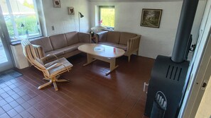A living room with a sofa, a round table, and a fireplace. - Bright holiday home near beach and coast (Hejls)
