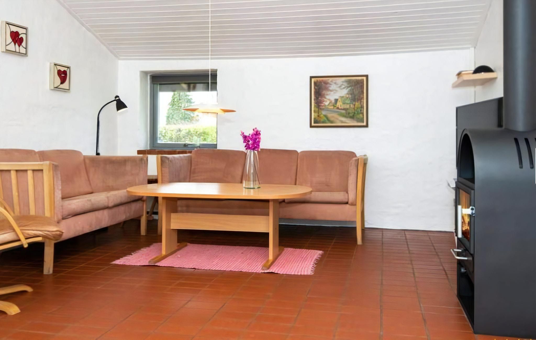 Ein Wohnzimmer mit einer Couch, einem Holztisch, einem rosa Teppich, einem Kamin und einem Bild an der Wand.