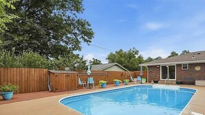 A backyard with a swimming pool, wooden fence, and outdoor furniture. - Poolside Pokes...Walk to OSU!!! (Stillwater)