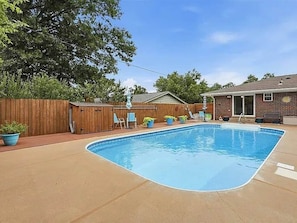 A backyard with a swimming pool, wooden fence, and outdoor furniture. - Poolside Pokes...Walk to OSU!!! (Stillwater)