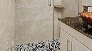 A glass-enclosed shower with a handheld showerhead, a tiled backsplash, and a countertop with a vessel sink. - Poolside Pokes...Walk to OSU!!! (Stillwater)