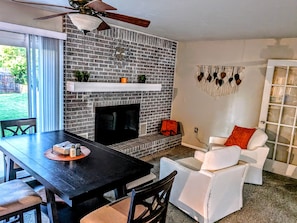A living room with a brick fireplace, a ceiling fan, a white sofa, and a dining table.
