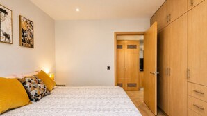 Un dormitorio con una cama, un armario y una puerta que da a otra habitación.