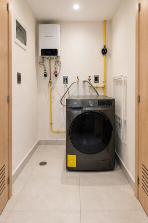 Ein kleiner Hauswirtschaftsraum mit einer Waschmaschine mit Frontlader, einem Warmwasserbereiter und einer Heizung.