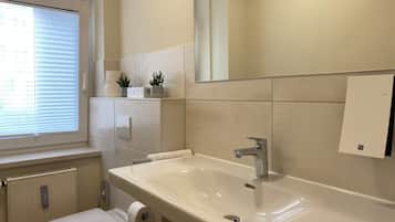 A bathroom with a toilet, sink, and window with blinds.