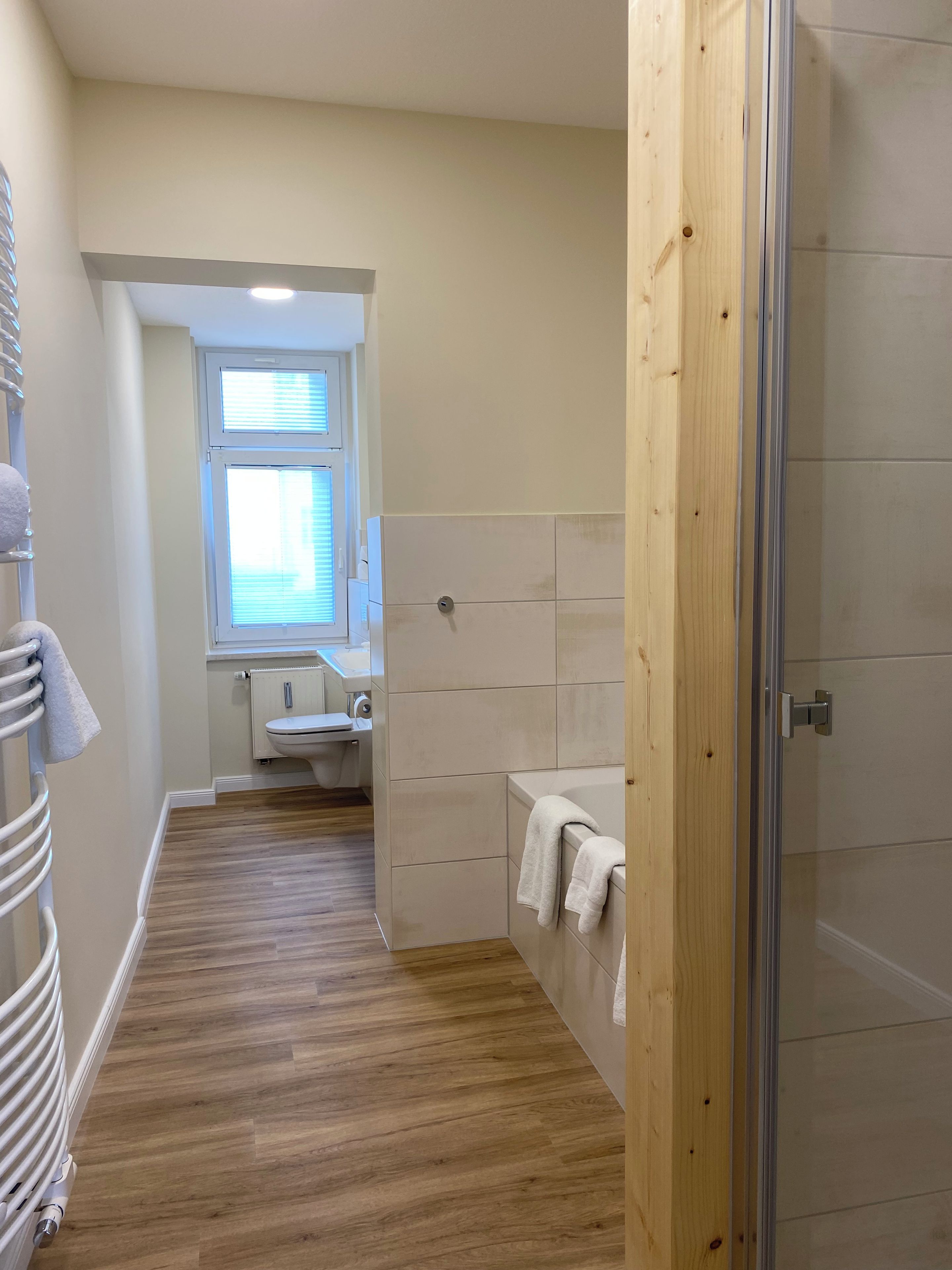 Ein Badezimmer mit Holzboden, einer Duschkabine, einer Toilette und einem Waschbecken.
