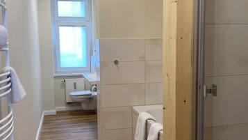 Ein Badezimmer mit Holzboden, einer Duschkabine, einer Toilette und einem Waschbecken.