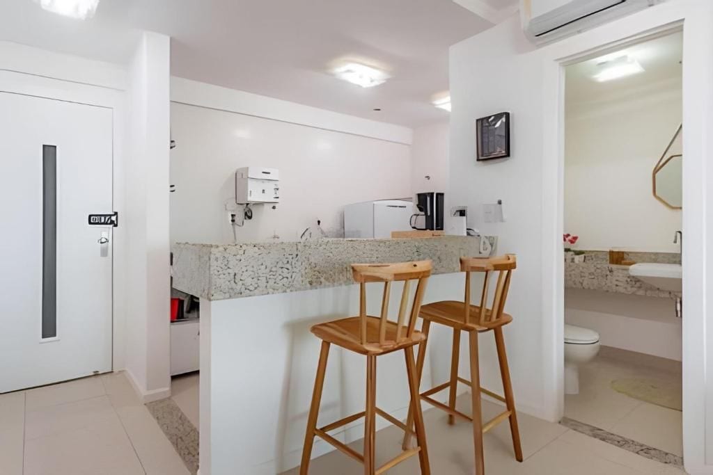 Cozinha moderna com bancada de granito, dois banquetes de madeira, cafeteira e geladeira.