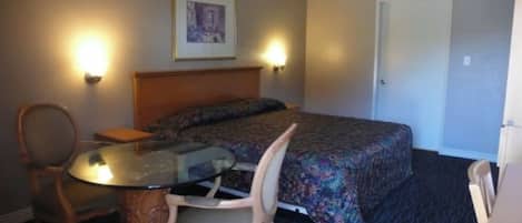 Una habitación de hotel con una cama, una silla, una mesa y dos lámparas de pared.
