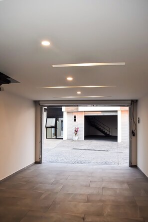 Un espacio interior con piso de baldosas, techo con iluminación empotrada y un acceso a zona exterior con escalera.