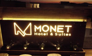Une enseigne « A MONET Hotel & Suites » au design moderne, avec des lettres illuminées.
