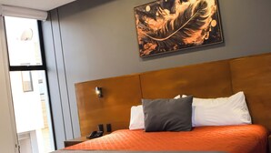 Habitació d'hotel moderna amb un llit gran, un quadre a la paret i vista exterior.
